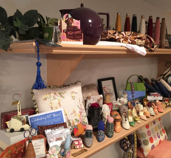 Shelves mounted on the wall with sewing themed collectibles on display.