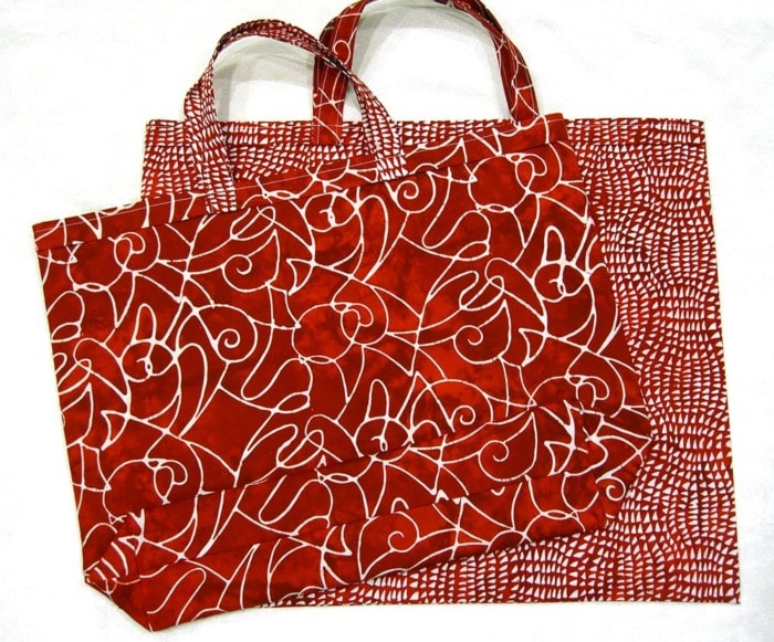 With Two red batik fabric tote bags made from the With Love Tote Bag Free sewing pattern.