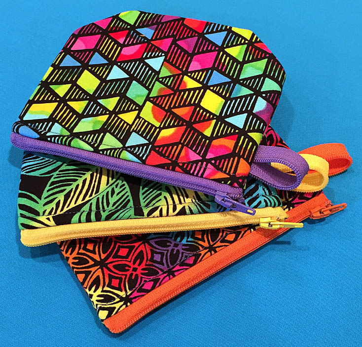 Three small zipper pouches in bright fabrics and zippers.