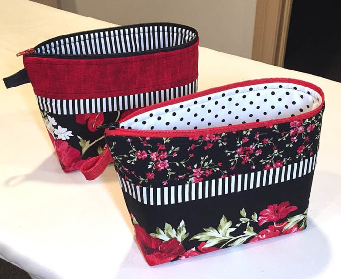 Small zippered pouch made with a border print of florals on a black background.