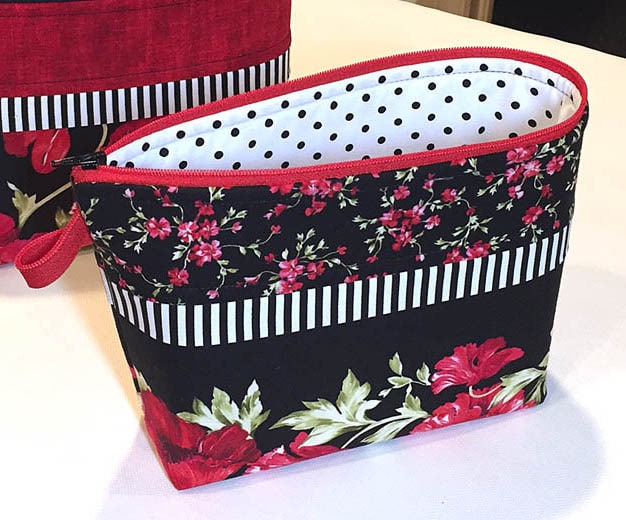 Small zippered pouch made with a border print of florals on a black background.