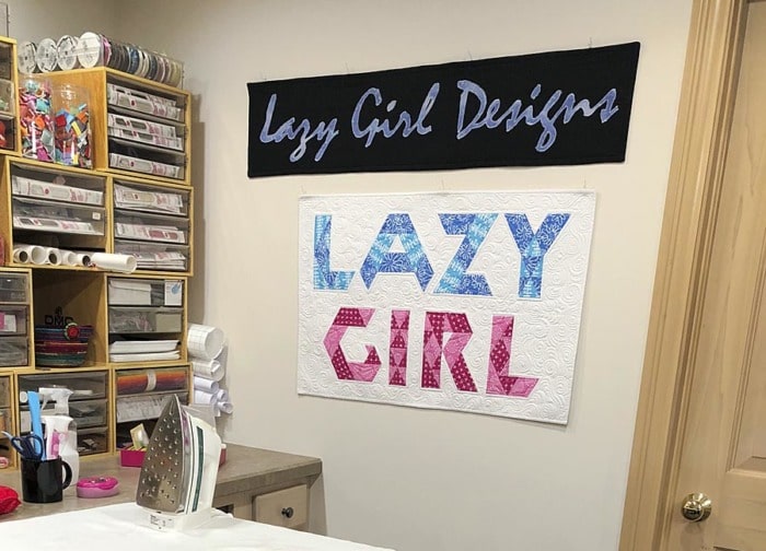 Display of fabric signs made by applique and patchwork for Lazy Girl Designs pattern company