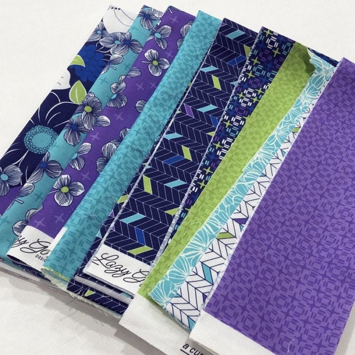 Close up view of sewing tip of how to arrange several fabrics from a single fabric collection in purples, blues, and teals.