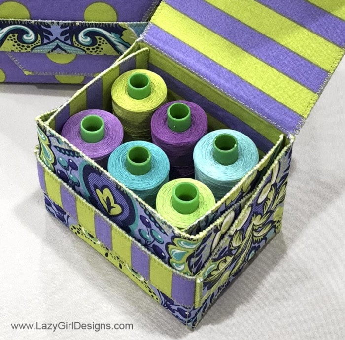 Gift box filled with colorful spools of thread.